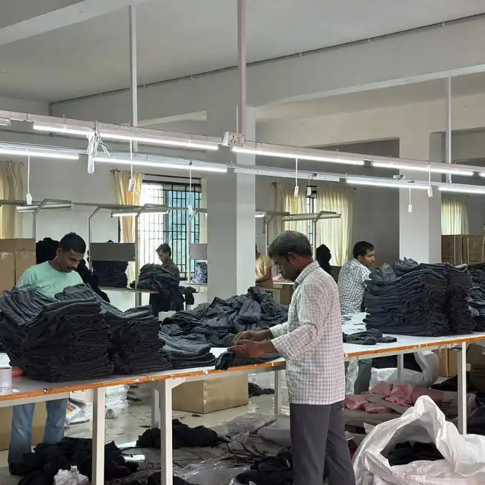 Quality control supervisors checking stitched black executive trousers before bulk dispatch