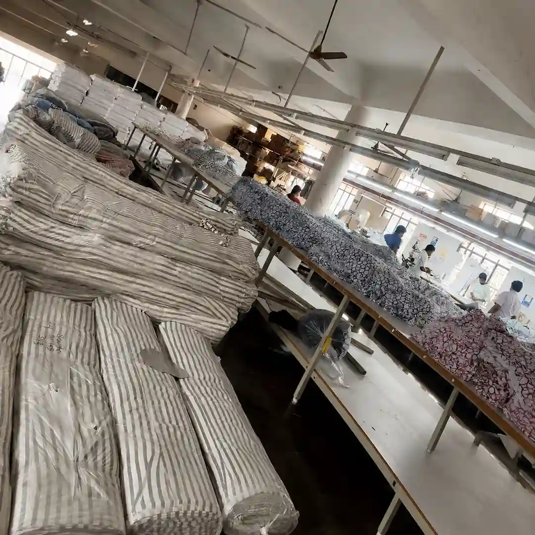 Textile manufacturing warehouse setup with striped fabric rolls and workers at cutting tables